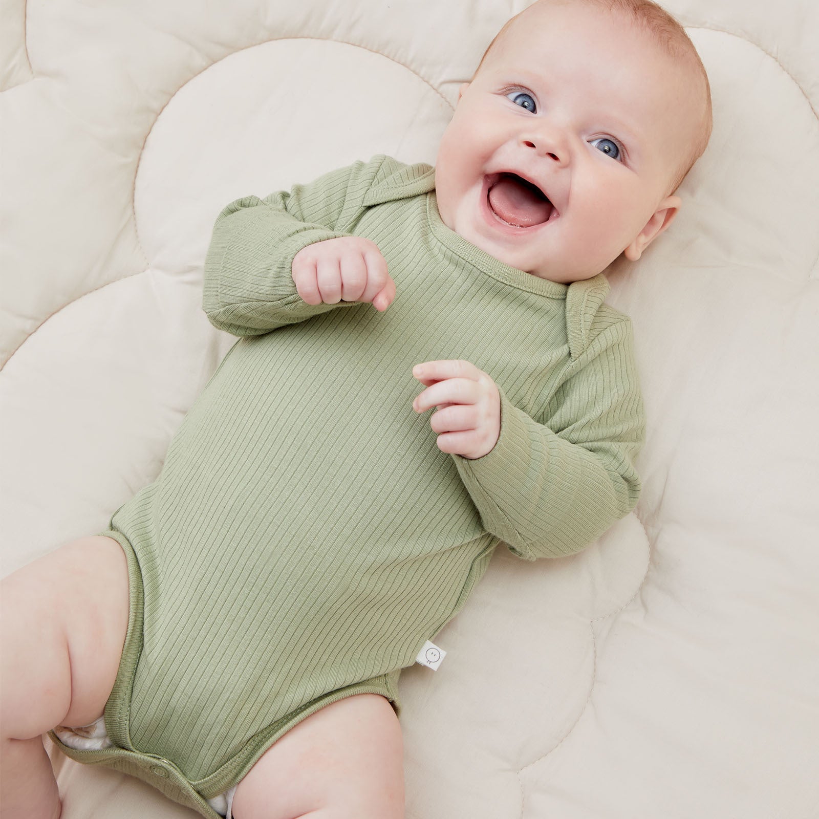 smiling baby in sage ribbed long-sleeve bodysuit made from organic cotton and bamboo